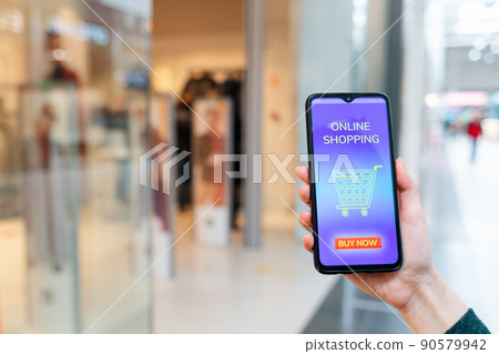 A female's hand shows a cellphone with a promo code for a discount at an online store. Blurred background. The concept of internet shopping A female's hand shows a cellphone with a promo code for a discount at an online store. Blurred background. The concept of internet shopping 90579942