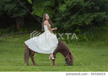 girl in a white dress riding a pony girl in a white dress riding a pony 90580028