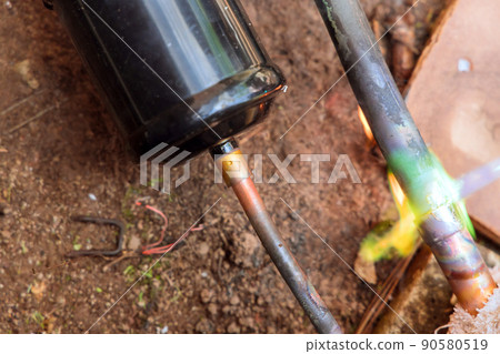 HVAC technician soldering a copper pipe joint for air conditioning 90580519