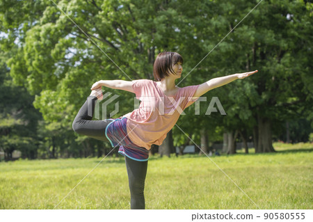 Young woman doing yoga on the grass in the park 90580555