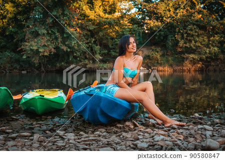 Kayaking. A beautiful smiling young woman in a poses sitting on a kayak. Recretion at the national park 90580847