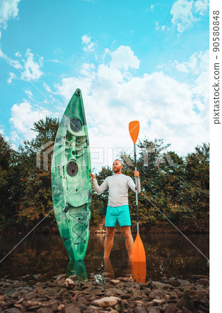 Kayaking. A man standing at the river and posing with kayak. Vertical. Recretion at the national park. Concept of World Tourism Day 90580848