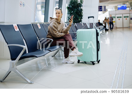 female tourist with a smartphone sitting in the airport waiting room . female tourist with a smartphone sitting in the airport waiting room . 90581639
