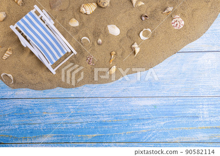 Sun lounger and seashells on the sand on a blue background Sun lounger and seashells on the sand on a blue background 90582114