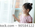 cute little girl is holding the white curtain with copy space 90584122