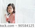 cute little girl is holding the white curtain with copy space 90584125