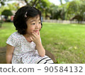 beautiful cute little girl sits and make a pose with smile in the garden with copy space 90584132