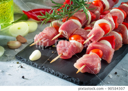 Fresh meat kebab. Meat fillet raw with cherry tomatoes, onions, spices and rosemary on a cutting board, preparation of barbecue. Fresh meat kebab. Meat fillet raw with cherry tomatoes, onions, spices and rosemary on a cutting board, preparation of barbecue. 90584307