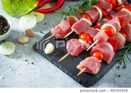 Fresh meat kebab. Meat fillet raw with cherry tomatoes, onions, spices and rosemary on a cutting board, preparation of barbecue. Copy space. Fresh meat kebab. Meat fillet raw with cherry tomatoes, onions, spices and rosemary on a cutting board, preparation of barbecue. Copy space. 90584308