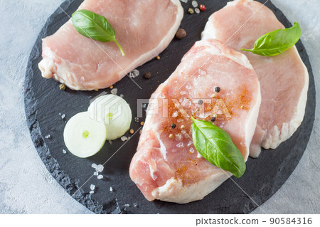 Raw sirloin steak with basil, onion and spices cooking on the stone kitchen table. Raw sirloin steak with basil, onion and spices cooking on the stone kitchen table. 90584316