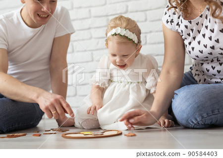 Child girl with cochlear implant plays at home with mother and father. Hear impairment and diversity and hearing aid 90584403