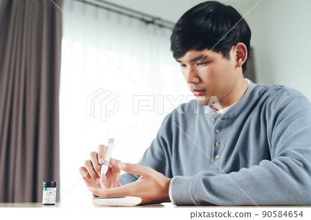 Asian man using lancet on finger for checking blood sugar level by Glucose meter, Healthcare and Medical, diabetes, glycemia concept 90584654