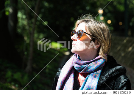 Attractive thirty year old woman posing in the sun, in a Brussels citypark during spring Attractive thirty year old woman posing in the sun, in a Brussels citypark during spring 90585029
