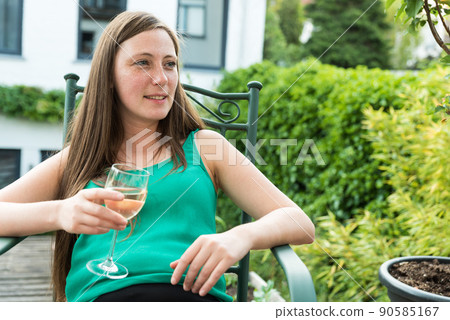 Portrait of an attractive thirty year old woman drinking wine in her garden at home 90585167
