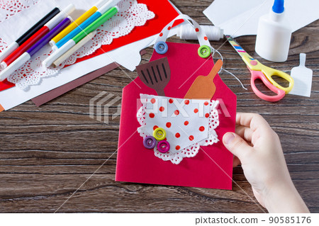 Creates a baby gift from a paper apron postcard for grandmother on mother's day. Hand-made. The project of children's creativity, needlework, crafts for children. 90585176