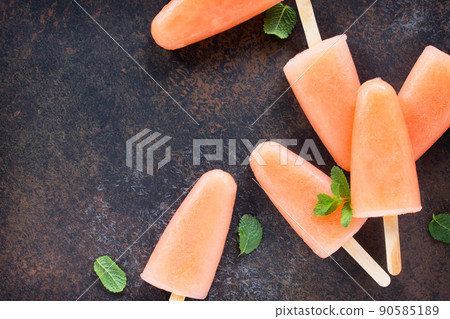 Delicious fruit ice grapefruit and mint on a stone background. Top view with copy space. Delicious fruit ice grapefruit and mint on a stone background. Top view with copy space. 90585189
