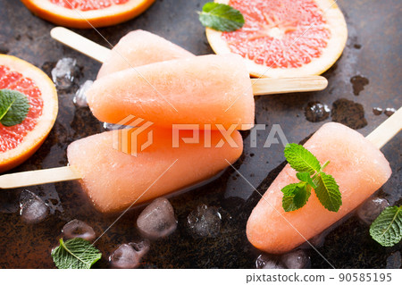 Delicious fruit ice grapefruit and ice on a stone background. 90585195