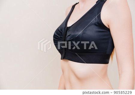A young woman in black compression underwear after mammoplasty. 90585229