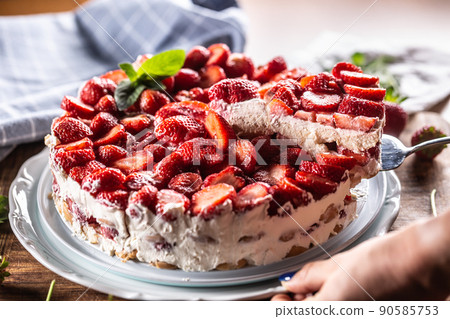 Woman's hand slices strawberry cream pie - Close up Woman's hand slices strawberry cream pie - Close up 90585753