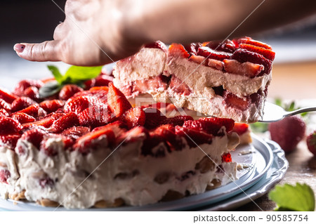Woman's hand slices strawberry cream pie - Close up Woman's hand slices strawberry cream pie - Close up 90585754