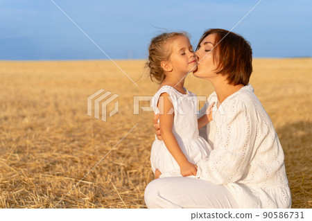 Mom kisses daughter cheek wheat field. Mother kiss little girl 90586731