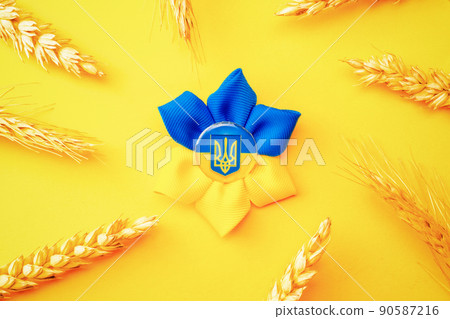 Blue yellow background. Ukrainian flower trident symbol with wheat grain ear isolated on yellow. Love Ukraine concept. Blue yellow background. Ukrainian flower trident symbol with wheat grain ear isolated on yellow. Love Ukraine concept. 90587216