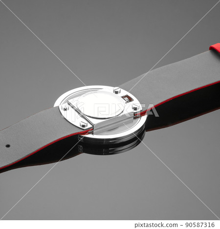 Close-up shot of a watch placed upside down on a reflecting surface. 90587316