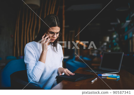 Serious woman using smartphone for making call Serious woman using smartphone for making call 90587341