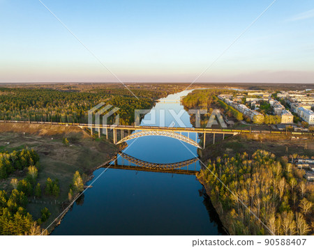 Beautiful view of the arched railway bridge across the Iset River in the city of Kamenkk-Uralsky at sunset in spring. Kamensk-Uralskiy, Sverdlovsk region, Ural mountains, Russia. 90588407