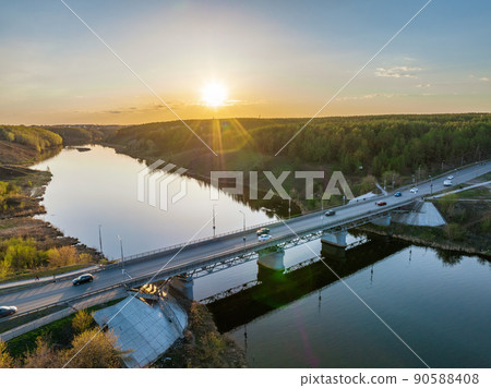 Beautiful view of the bridge across the Iset river in the city of Kamensk-Uralsky at sunset in spring. Kamensk-Uralskiy, Sverdlovsk region, Ural mountains, Russia. 90588408