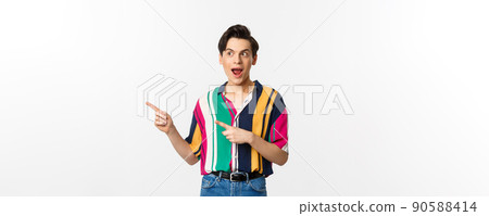 Excited happy man pointing left at promo banner, looking amazed, standing against white background Excited happy man pointing left at promo banner, looking amazed, standing against white background 90588414