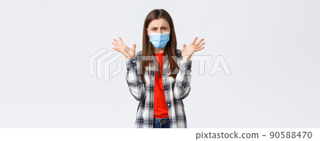 Different emotions, covid-19 pandemic, coronavirus self-quarantine and social distancing concept. Angry, outraged woman in medical mask, arguing, look mad, raise hands in dismay, complaining 90588470
