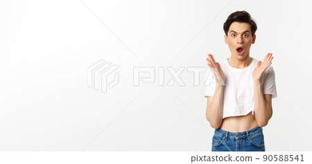 Lgbtq and pride concept. Image of surprised queer guy clap hands and looking in awe at camera, standing in crop top against white background 90588541