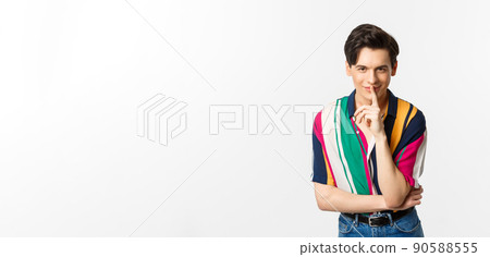 Portrait of young handsome man prepare surprise, hushing and smiling, telling secret, standing over white background Portrait of young handsome man prepare surprise, hushing and smiling, telling secret, standing over white background 90588555