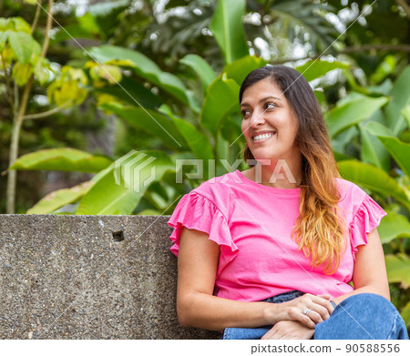 latina woman sitting in a bench in the park latina woman sitting in a bench in the park 90588556