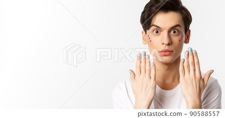 People, lgbtq and beauty concept. Beautiful gay man showing blue nail polish on fingernails and looking at camera, have manicure, standing over white background People, lgbtq and beauty concept. Beautiful gay man showing blue nail polish on fingernails and looking at camera, have manicure, standing over white background 90588557