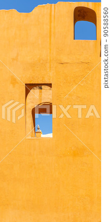 Vertical photo of a yellow wall with windows and blue sky 90588560