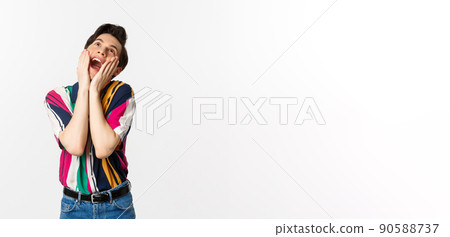 Image of excited gay man shouting of joy and looking up, feeling ecstatic, standing against white background 90588737