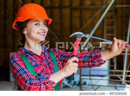 teen girl builder in protective helmet use hammer, repair teen girl builder in protective helmet use hammer, repair 90589006