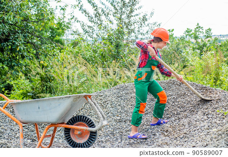 happy kid engineer with shovel and construction wheelbarrow in hard hat, construction 90589007