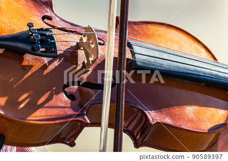 Bow and violin close-up. Detailed view of a man playing the violin in public. 90589397
