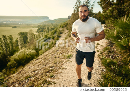Young muscular male athlete running up the hill 90589923