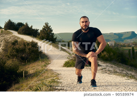 Male athlete warming up before start running in mountains Male athlete warming up before start running in mountains 90589974