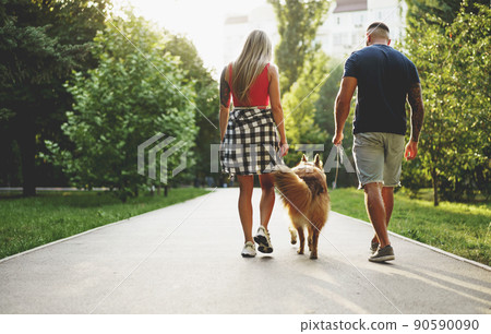 Young beautiful couple walking the dog in the summer park 90590090