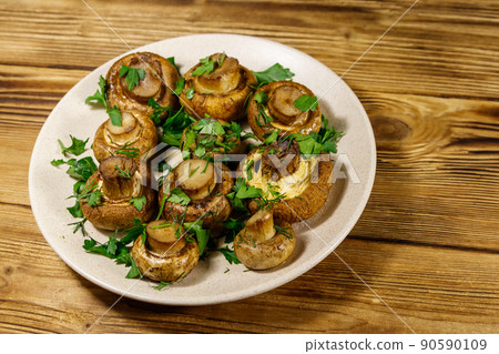 Baked mushrooms in plate on wooden table Baked mushrooms in plate on wooden table 90590109