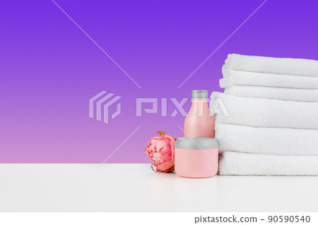 Stacked clean towels on white table against color background Stacked clean towels on white table against color background 90590540