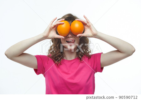 cheerful girl holding oranges imitating eyes, photo shoot in the studio on a white background cheerful girl holding oranges imitating eyes, photo shoot in the studio on a white background 90590712