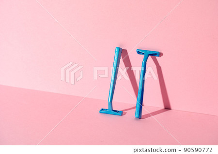 Blue disposable razors on pink paper background Blue disposable razors on pink paper background 90590772