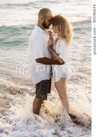 Beautiful young couple hugging on the beach by the water 90590834