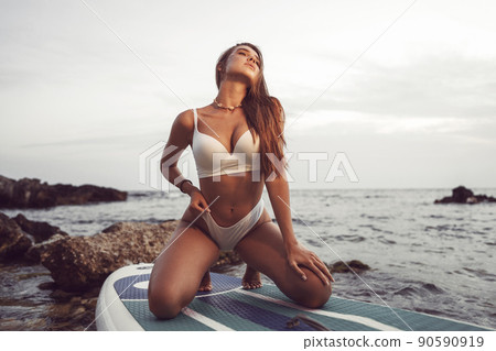 Young beautiful sexy woman posing in sea on a SUP board Young beautiful sexy woman posing in sea on a SUP board 90590919